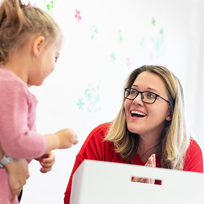 a smiling professional looking at a young girl held by her parent